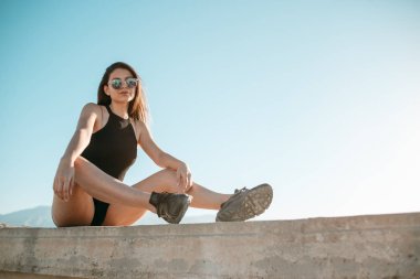 Genç güzel kız siyah şort ve çatıda günbatımında poz üst