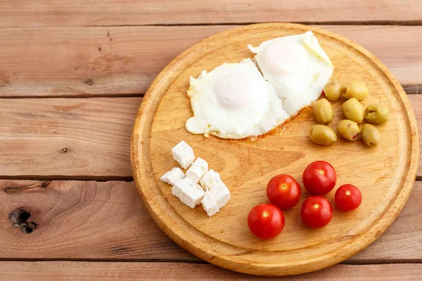 Ontbijt Gebakken Eieren Tomaten Olijven Kaas Een Houten Plaat Bovenaanzicht — Stockfoto