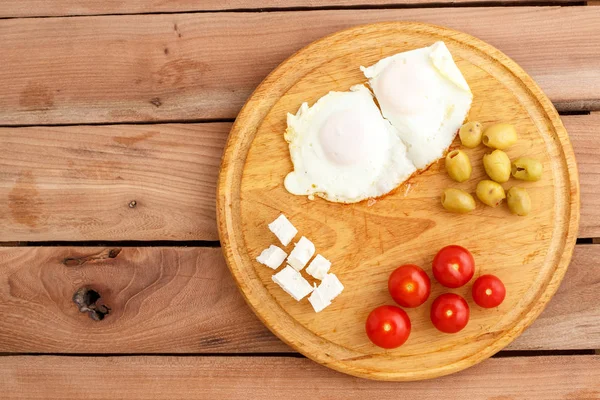 Ontbijt Gebakken Eieren Tomaten Olijven Kaas Een Houten Plaat Bovenaanzicht — Stockfoto
