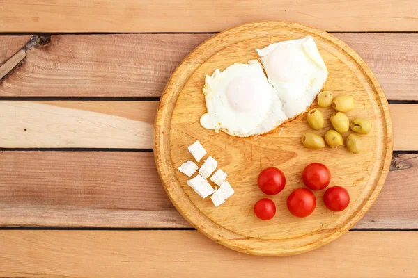Ontbijt Gebakken Eieren Tomaten Olijven Kaas Een Houten Plaat Bovenaanzicht — Stockfoto