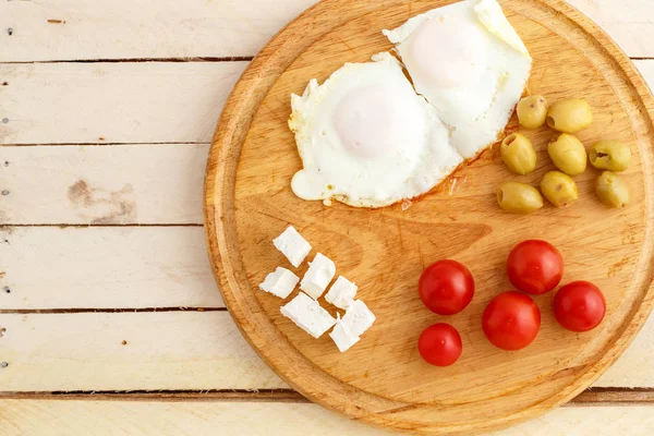 Ontbijt Gebakken Eieren Tomaten Olijven Kaas Een Houten Plaat Bovenaanzicht — Stockfoto