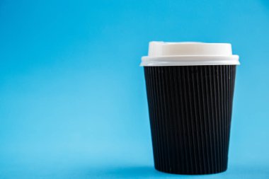 Mavi bir arka plan üzerinde izole karton tek kullanımlık bardak. Önden Görünüm