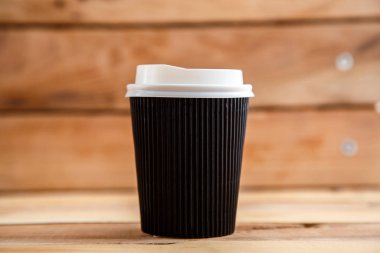 Ahşap arka plan üzerinde izole karton tek kullanımlık bardak. Önden Görünüm