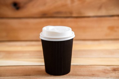 Ahşap arka plan üzerinde izole karton tek kullanımlık bardak. Önden Görünüm