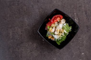 Sezar salatası siyah bir tabakta. üstten görünüm