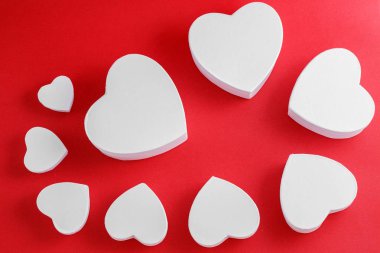 white heart-shaped cardboard boxes on red background