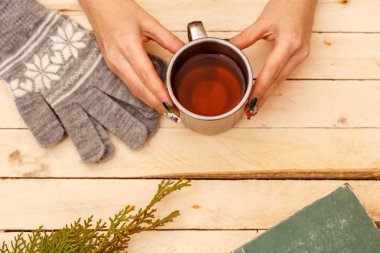 women's hands holding a vintage mug on a wooden background