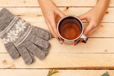 women's hands holding a vintage mug on a wooden background