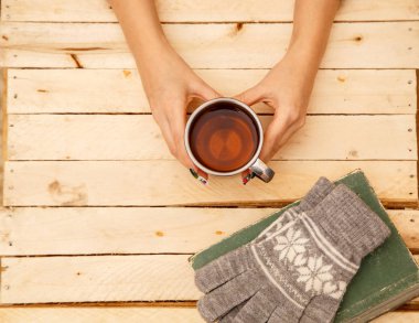 women's hands holding a vintage mug on a wooden background