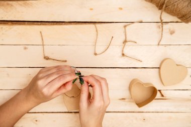 women's hands spread hearts and the word love of threads on a light wooden background. the view from the top