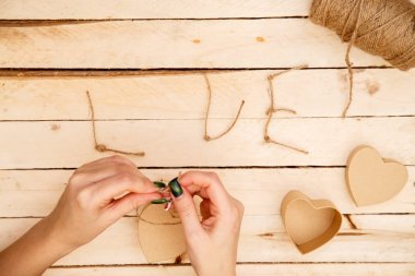 women's hands spread hearts and the word love of threads on a light wooden background. the view from the top