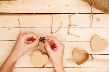 women's hands spread hearts and the word love of threads on a light wooden background. the view from the top
