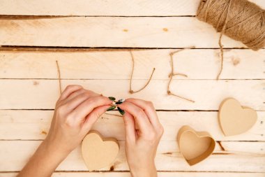 women's hands spread hearts and the word love of threads on a light wooden background. the view from the top