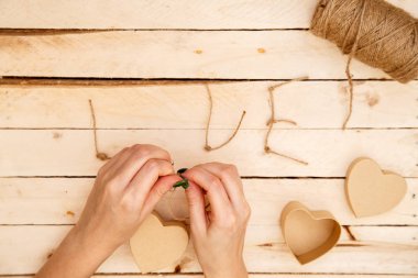 women's hands spread hearts and the word love of threads on a light wooden background. the view from the top