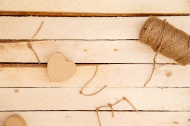 women's hands spread hearts and the word love of threads on a light wooden background. the view from the top