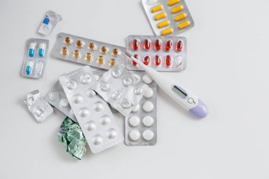 beyaz izole arka plan üzerinde elektronik termometre ve ilaçlar