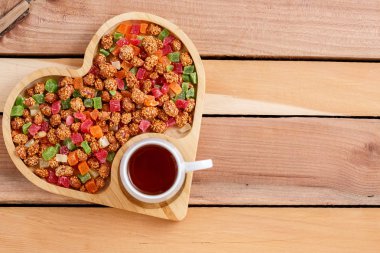 renkli kurutulmuş meyve, çay ve ahşap bir arka plan üzerinde kalp şeklinde bir hediye