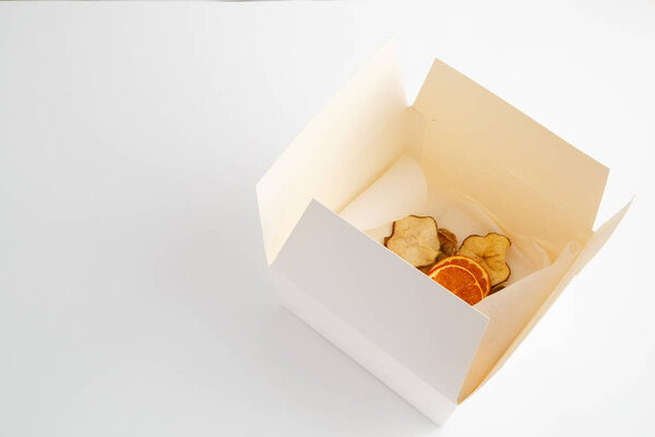 dried oranges,bananas and apples in white box on white backgroun