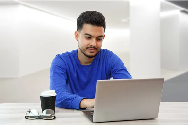 Молодой парень, сидящий за ноутбуком в поисках работы на Интерне — стоковое фото