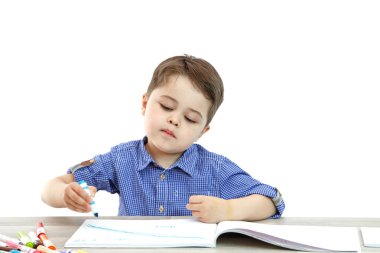 küçük çocuk oturur ve izole bir arka plan üzerinde yazıyor çizer