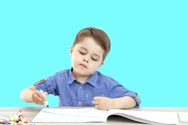 Menino se senta e desenha escreve em um fundo isolado — Fotografia de Stock