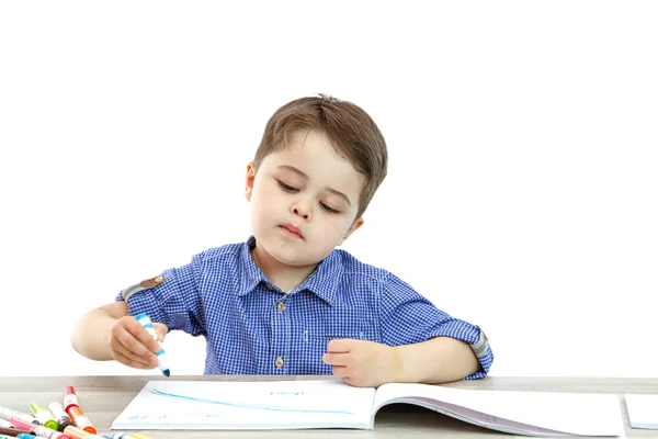 Mały chłopak siedzi i rysuje pisze na białym tle — Zdjęcie stockowe