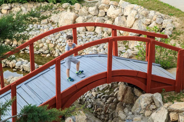 Um menino caminha através da ponte e sorri — Fotografia de Stock