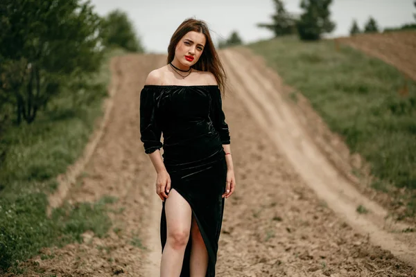 Young beautiful woman in black dress posing for a photographer o — 스톡 사진