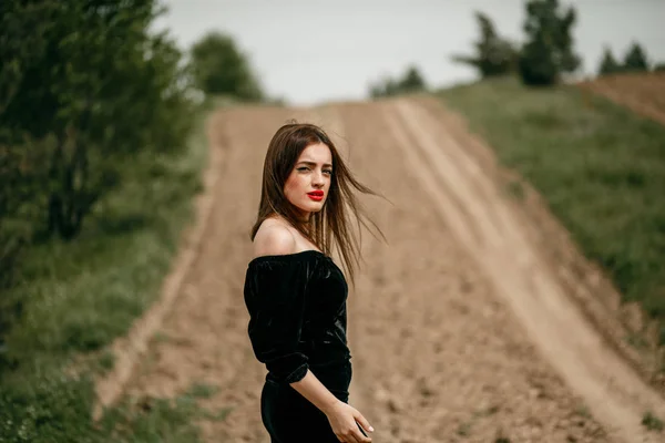 Jovem mulher bonita em vestido preto posando para um fotógrafo o — Fotografia de Stock