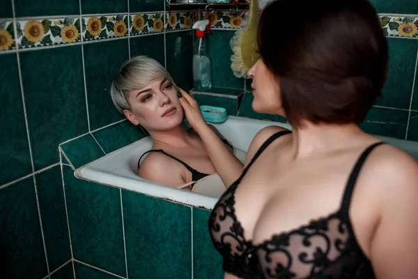 Blondýnka s brunetou v koupelně ve spodním prádle vzájemně se dotýkejte — Stock fotografie