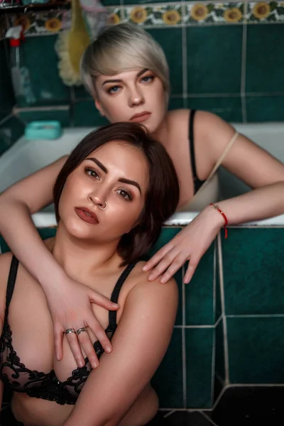 Блондинка з брюнеткою у ванній в нижній білизні торкаються один одного — стокове фото