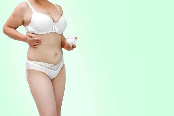 Uma mulher com excesso de peso em roupa interior branca aplicando creme em — Fotografia de Stock