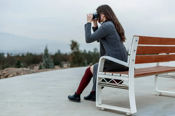 Young beautiful girl in Burgundy stockings and gray coat sitting — 스톡 사진