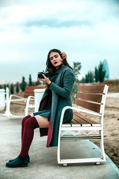 Young beautiful girl in Burgundy stockings and gray coat sitting — 스톡 사진