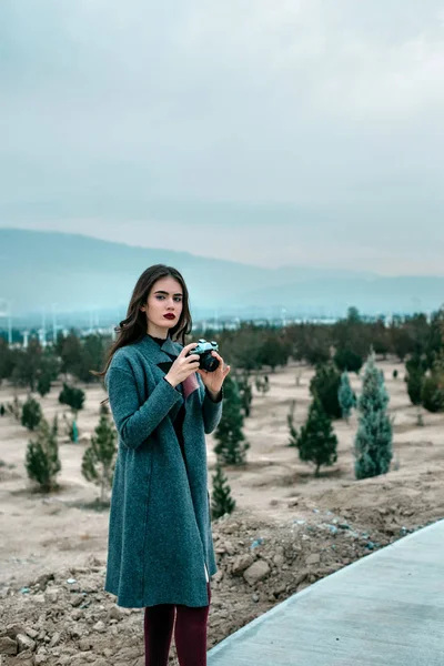 Joven hermosa chica en Borgoña medias y gris abrigo stands — Foto de Stock