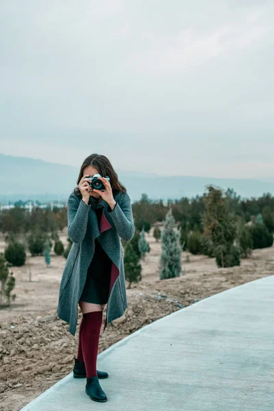 สาวสวยในถุงเท้าเบอร์กันดีและเสื้อโค้ทสีเทายืน — ภาพถ่ายสต็อก