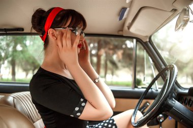 siyah vintage elbise ve vintage gözlük bir vintage arabanın direksiyonuna poz Kafkas güzel genç kız portresi