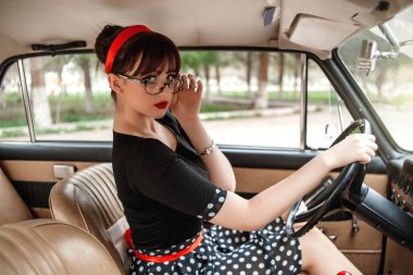 siyah vintage elbise ve vintage gözlük bir vintage arabanın direksiyonuna poz Kafkas güzel genç kız portresi