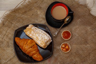 Eclair, siyah bir tabak ve kahve zekâ bir Fincan üzerinde puf tatlı tüp