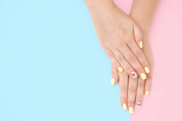 Manos de las mujeres con una hermosa manicura con dibujos de pasteles a — Foto de Stock