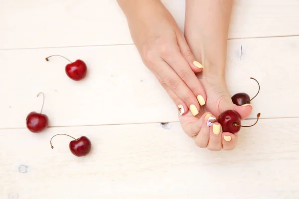 Manos de las mujeres con una hermosa manicura con dibujos de pasteles o — Foto de Stock