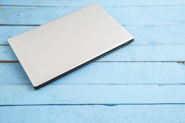 Mavi ahşap arka planda gri bir laptop. Yukarıdan görünüm