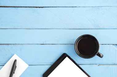 bir Fincan içecek, siyah bir tablet, küçük bir kağıt defter ve bir bla