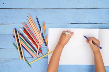 çocuk elleri mavi tabl üzerinde albümde kalemler ile çizmek
