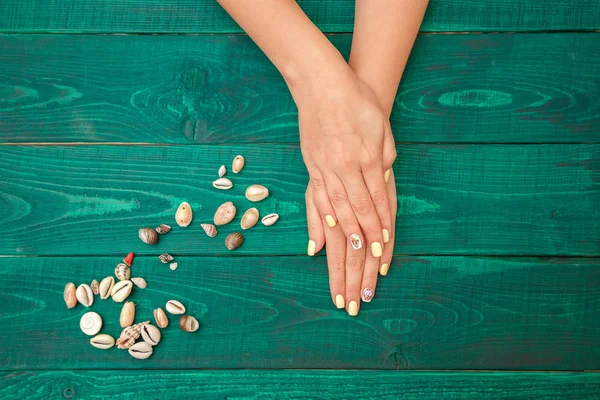 Manos de las mujeres con una hermosa manicura con un patrón de verano un — Foto de Stock