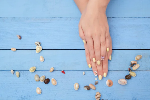 Manos de las mujeres con una hermosa manicura con un patrón de verano un — Foto de Stock