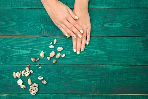 Manos de las mujeres con una hermosa manicura con un patrón de verano un — Foto de Stock