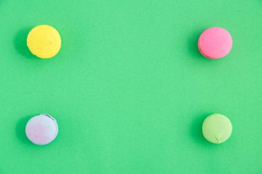 yeşil arka plan üzerinde renkli macarons veya macaroons çerezleri. Sayfanın Üstü 