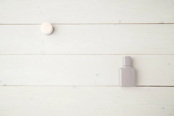 Botella gris con perfume y cosméticos en un fondo de madera claro — Foto de Stock