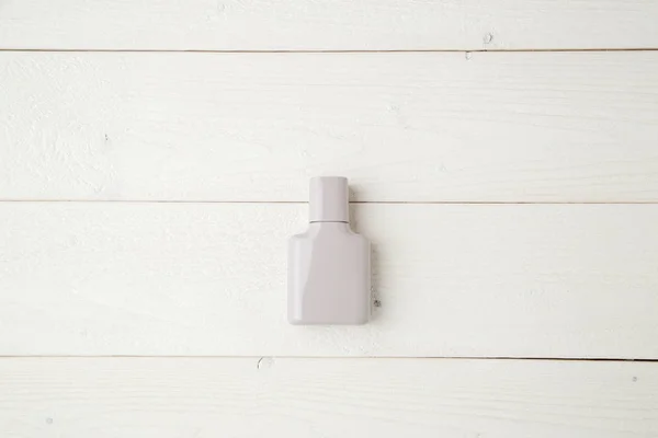 Frasco gris de perfume sobre un fondo de madera clara. plano laico — Foto de Stock
